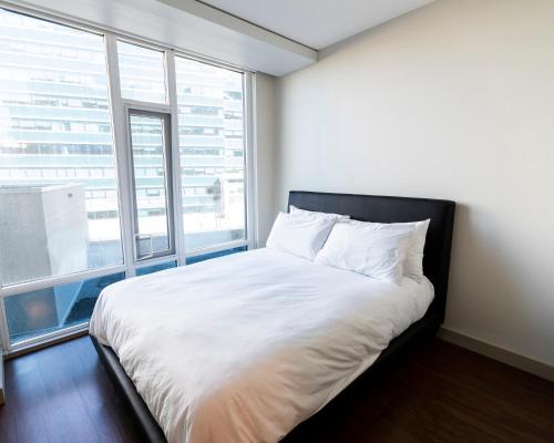 een slaapkamer met een wit bed en een groot raam bij Mayfair by Corporate Stays in Edmonton