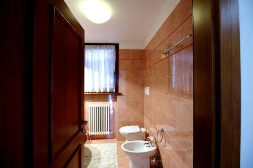 a bathroom with a toilet and a sink and a window at Nonostantetutto B&B in Pieve di Cadore