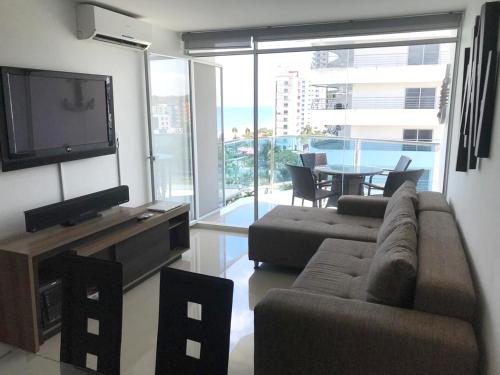 a living room with a couch and a television and a table at Espectacular, frente al mar in Tonsupa