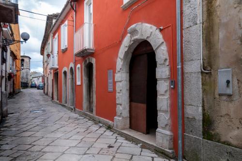 an alley with an arch in a red building at Boutique Hotel Palazzo Corso Umberto in Boiano