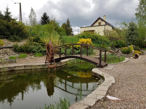 a wooden bridge over a pond in a garden at Agroturystyka u Kasi in Kłodzko