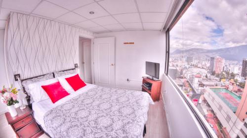 1 dormitorio con 1 cama y TV en el balcón en Executive Suite, en Quito