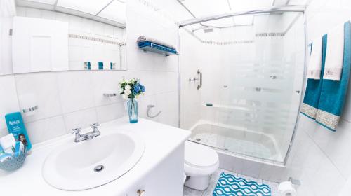 Baño blanco con lavabo y aseo en Executive Suite, en Quito