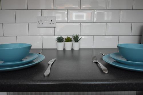 een tafel met twee blauwe kommen en borden en bestek bij Dwell Living - No 61 in Sunderland
