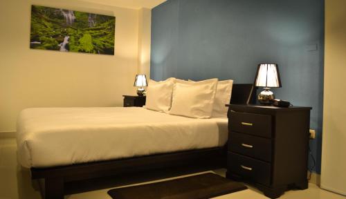a bedroom with a bed and a nightstand with two lamps at Wayak Hotel in Managua