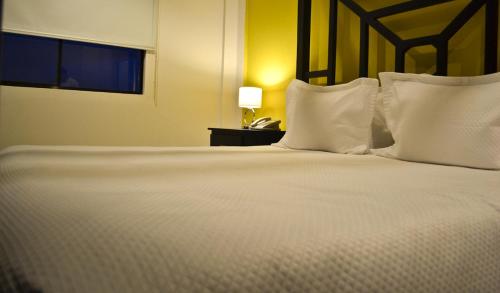 a large white bed with pillows and a lamp on a table at Wayak Hotel in Managua