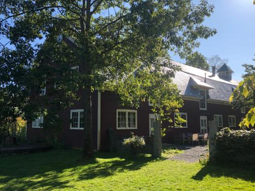 a red house with a tree in front of it at Gedney Farm in New Marlborough