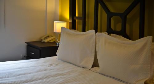a bed with white pillows and a phone on a table at Wayak Hotel in Managua