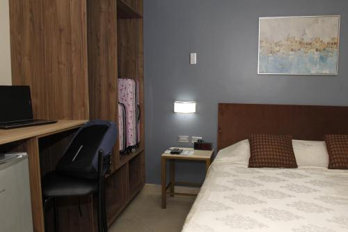 a bedroom with a bed and a desk with a laptop at Hotel Varadero Internacional in Guayaquil