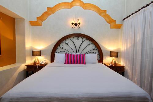 a bedroom with a large white bed with a red pillow at Hotel Tr&eacute;bol in Oaxaca City