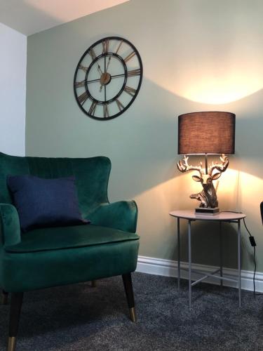 a living room with a green couch and a clock at The Nook - Coorie Doon in Ayr