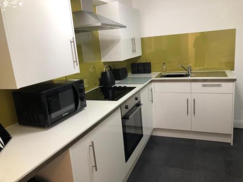 a kitchen with white cabinets and a microwave at The Nook - Coorie Doon in Ayr