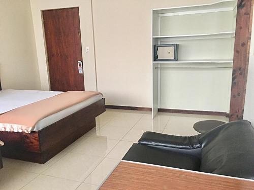 a bedroom with a bed and a chair and a tv at Hotel Ambassador in San José