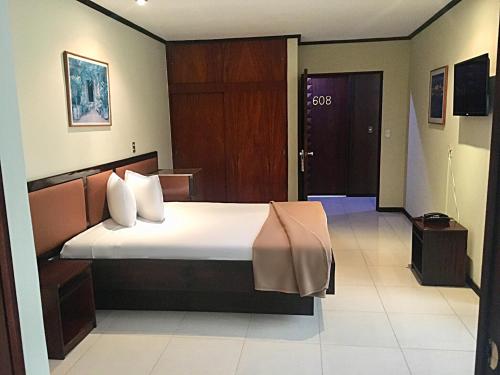 a hotel room with a bed and a door at Hotel Ambassador in San José