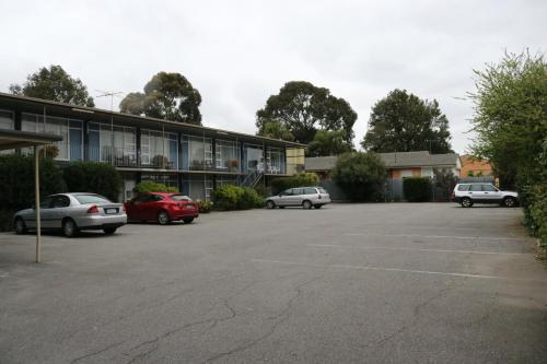 um parque de estacionamento com carros estacionados em frente a um edifício em The Sands Motel Adelaide em Adelaide