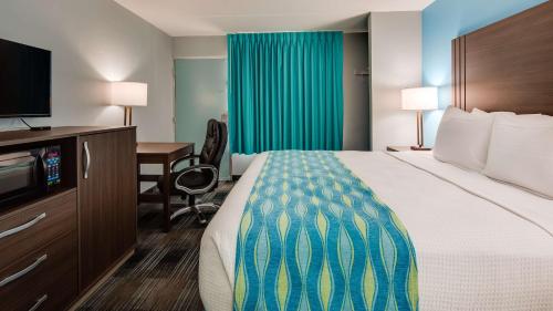 a hotel room with a bed and a desk and a television at SureStay Hotel by Best Western Jacksonville South in Jacksonville