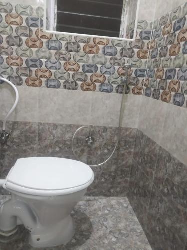 a bathroom with a toilet and a stone wall at Xavier Guest House in Chennai