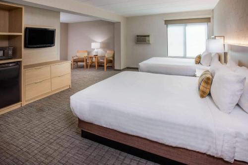 a hotel room with two beds and a flat screen tv at Days Inn & Suites by Wyndham Duluth by the Mall in Duluth