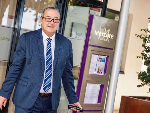 a man in a suit and tie standing in a building at Hotel Mercure Blois Centre in Blois