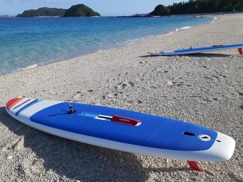two surfboards sitting on a beach next to the water at Shima Stay holoholo in Zamami