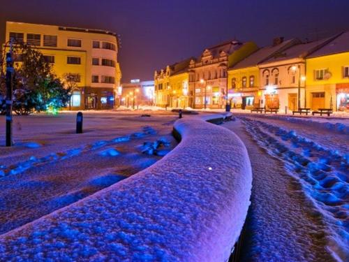 a street covered in snow at night with buildings at Chalupa Liptovský Mikuláš in Liptovský Mikuláš