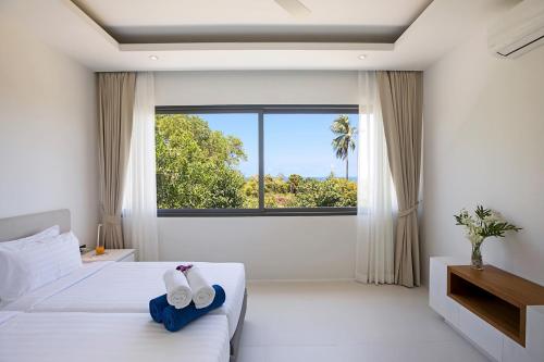 a bedroom with a large window and two towels on a bed at Sunway Holiday in Bang Rak Beach