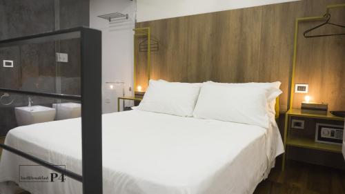 una camera da letto con un grande letto bianco con testiera in legno di P4 Ortigia_Siracusa a Siracusa