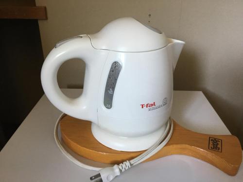 a white tea kettle on a stand on a counter at Miyajima Morinoyado in Miyajima