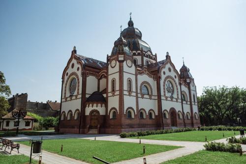 a large building with a grass yard in front of it at Apartment Rea in Subotica