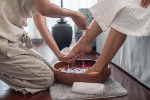 a man and a woman are washing their feet in a bowl at Souphattra Hotel Luang Prabang in Luang Prabang