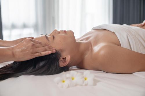 a woman laying on a bed getting a massage at Souphattra Hotel Luang Prabang in Luang Prabang
