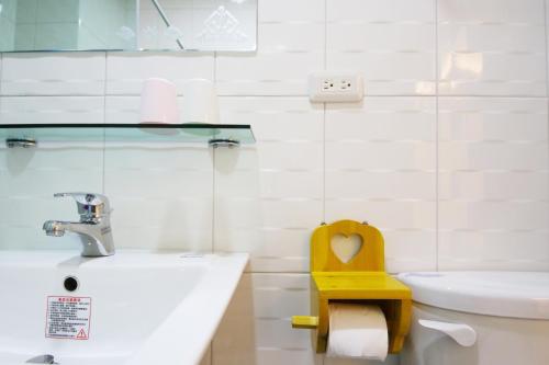 a bathroom with a sink and a toilet with a yellow seat at The Wind BnB Ⅱ in Budai