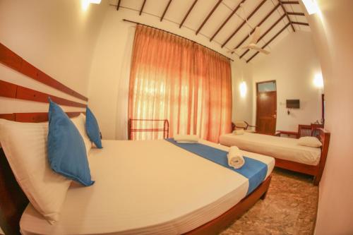 sypialnia z 2 łóżkami i niebieskimi poduszkami w obiekcie White Rose Beach Resort w mieście Marawila
