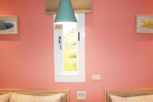 a bedroom with a red wall and a window at The Wind BnB Ⅱ in Budai