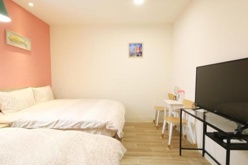 a bedroom with two beds and a flat screen tv at The Wind BnB Ⅱ in Budai
