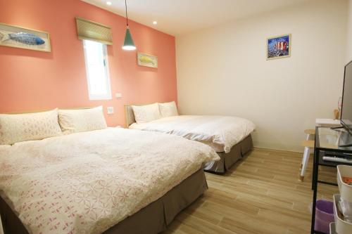 two beds in a room with orange walls at The Wind BnB Ⅱ in Budai