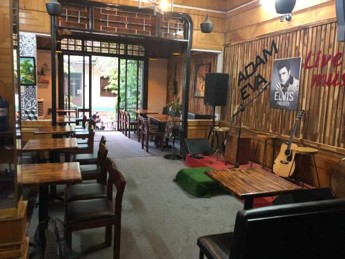 a restaurant with wooden tables and chairs and a guitar at Adam Eva Homestay in Dong Hoi