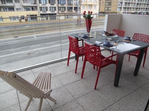 a table and chairs on a balcony with a view of a street at Osea Oostende in Ostend
