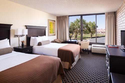 a hotel room with two beds and a desk and a window at Kayenta Monument Valley Inn in Kayenta
