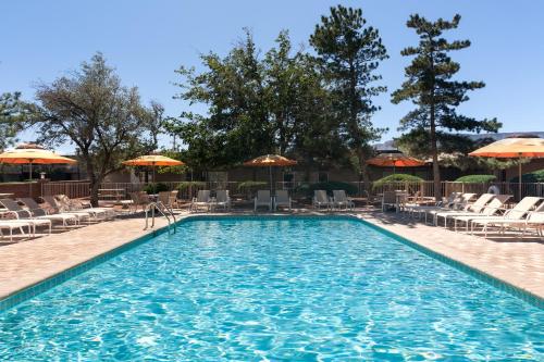 a swimming pool with chairs and umbrellas at Kayenta Monument Valley Inn in Kayenta