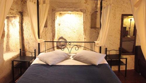 a bedroom with a black bed with two windows at ROCA CAPPADOCIA in Ürgüp
