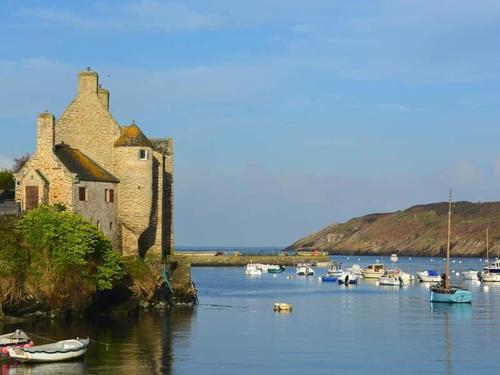 a group of boats in the water next to a building at Gite de kernaet avec piscine in Plougonvelin