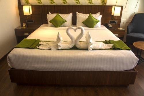 two swans shaped towels are on a bed at Hotel Ceasar Palace Kottayam in Kottayam