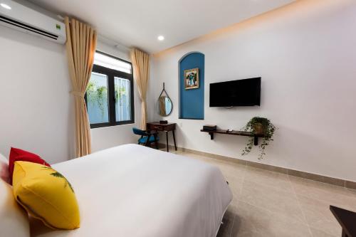 1 dormitorio con 1 cama blanca y TV en Chez Mimosa Petite - Free Laundry, en Ho Chi Minh