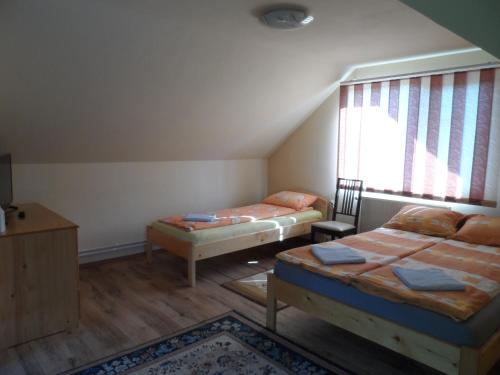 ソバタにあるAmigo Sovataのベッド2台と窓が備わる屋根裏部屋です。