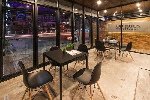 a restaurant with black chairs and tables in a room at Sleep Station in Surat Thani