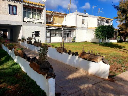 a house with a white retaining wall and some plants at casa penelope in Costa Del Silencio