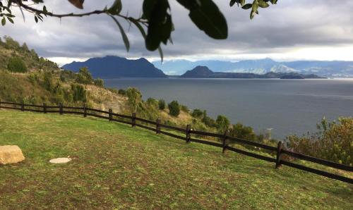 a fence on a hill with a view of the water at Casa La Trafa in Futrono