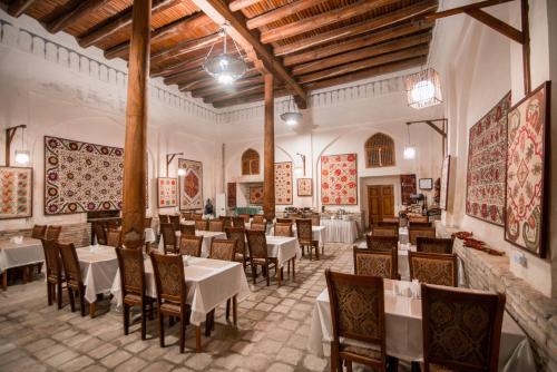 - un restaurant avec des tables et des chaises dans une salle dans l'établissement Boutique Hotel Minzifa, à Boukhara