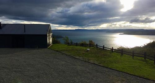 a barn on a hill next to a body of water at Casa La Trafa in Futrono